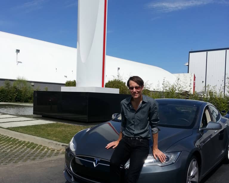 Andrew sitting on a Tesla at the Tesla car plant.